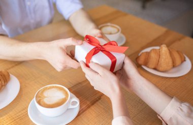 Milenyum çifti kahve dükkanında hediye kutusuyla yemek yiyor, Sevgililer Günü 'nü kutluyor, manzarayı kesiyor.