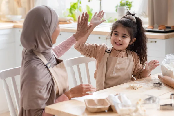 Mutlu Müslüman anne ve kızı mutfakta birbirlerine beşlik çakıyor. — Stok fotoğraf