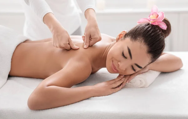 Mooie jonge aziatische vrouw ontspannen tijdens rug massage sessie in spa salon — Stockfoto