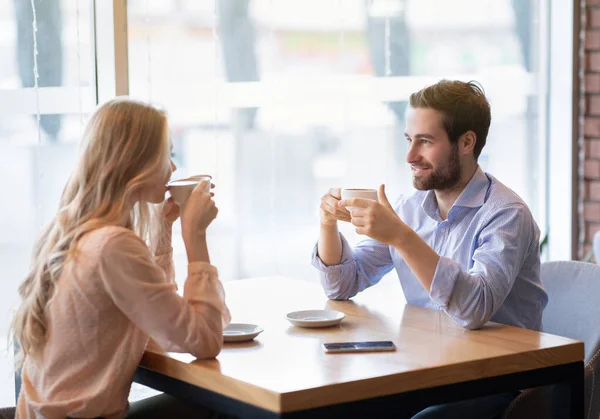 Retrato de pareja romántica encantadora sentada en la cafetería urbana con café fresco, disfrutando de su cita, tener una charla amistosa — Foto de Stock