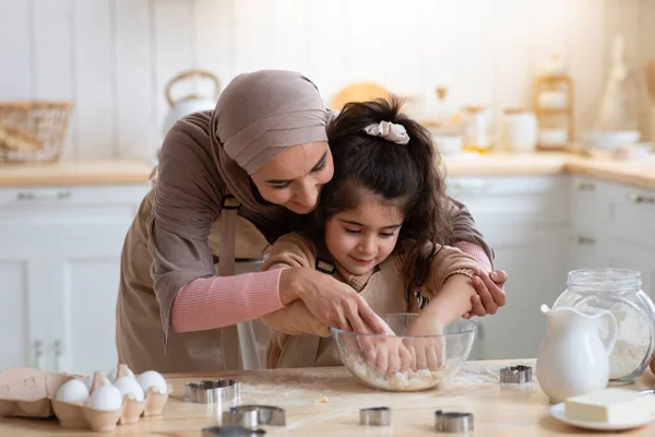 รักแม่มุสลิมสอนลูกสาววิธีการนวดแป้งในห้องครัว — ภาพถ่ายสต็อก
