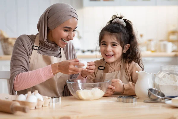 แม่อิสลามมีความสุขและลูกสาวที่น่ารักของเธอ เตรียมแป้งในครัวด้วยกัน — ภาพถ่ายสต็อก