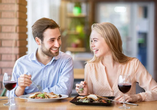 Schöne Dame mit ihrem Freund isst Salat und trinkt Wein, feiert Jubiläum zusammen im städtischen Café — Stockfoto