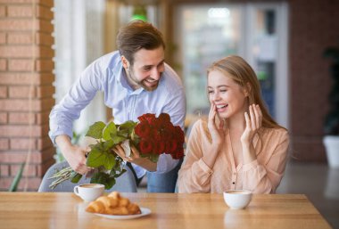 Sevecen bir milenyum erkeği sevgilisine sürpriz yapar, ona kafede çiçek verir.