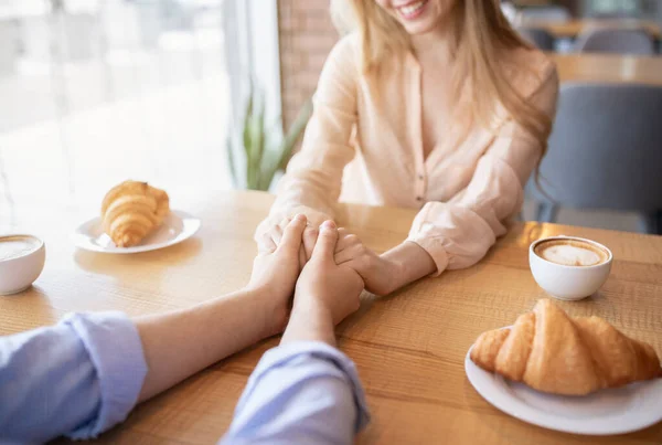 Pareja joven enamorada almorzando en la cafetería, cogidas de la mano, bebiendo café, vista de cerca —  Fotos de Stock