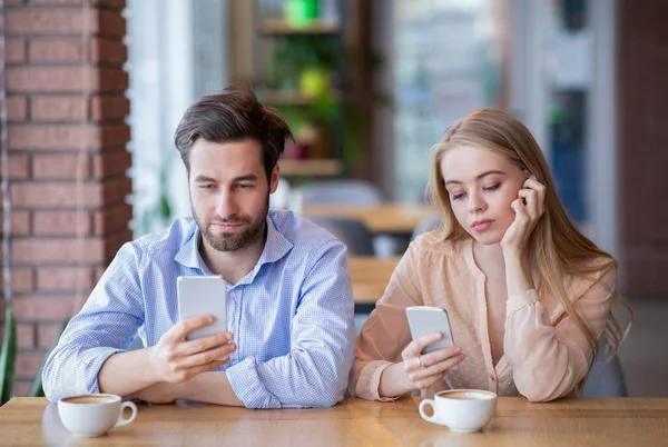 Smartphone závislost a phubbing koncept. Mladý pár na nudném rande, zaseklý v hračkách, zanedbávající jeden druhého v kavárně — Stock fotografie