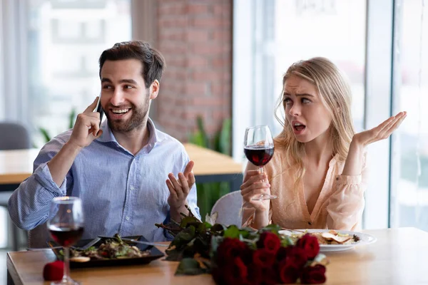 Millennial homem falando no celular em encontro romântico no café, sua namorada se sentindo entediado e negligenciado — Fotografia de Stock