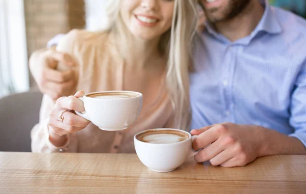 Widok na romantyczną parę pijącą kawę i przytulającą się w kawiarni — Zdjęcie stockowe