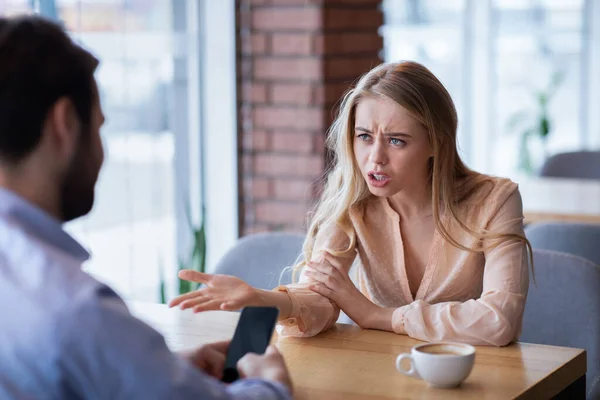 Dühös fiatal hölgy vitatkozik a barátjával az okostelefonon, boldogtalan az elhanyagolás és a kommunikáció hiánya miatt. — Stock Fotó