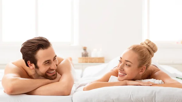 Cónyuges relajados en el spa acostados en camas sonriéndose mutuamente — Foto de Stock