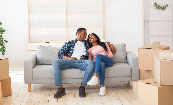 Fröhliche Millennial-Familie zieht um, macht Pause beim Auspacken, ruht sich auf Sofa zwischen Kartons aus — Stockfoto