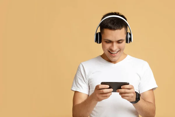 Entretenimento e jogos online para adolescentes. alegre bonito millennial cara no moderno sem fio fones de ouvido — Fotografia de Stock