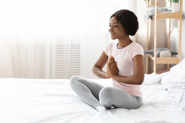 Wanita kulit hitam tersenyum duduk di tempat tidur dan bermeditasi — Stok Foto