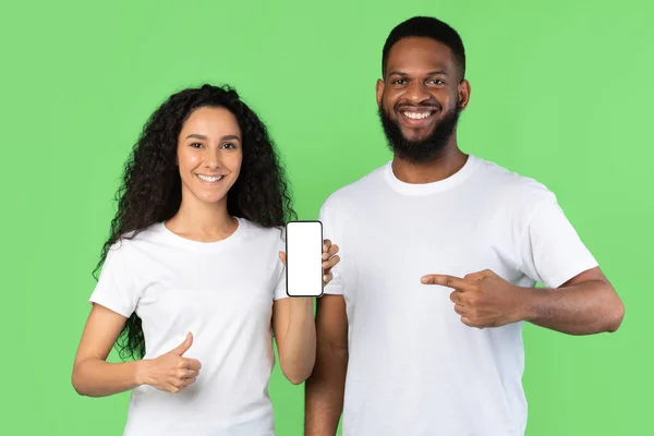 Par som visar telefon Tom skärm Gesturing tummen upp över grön bakgrund — Stockfoto