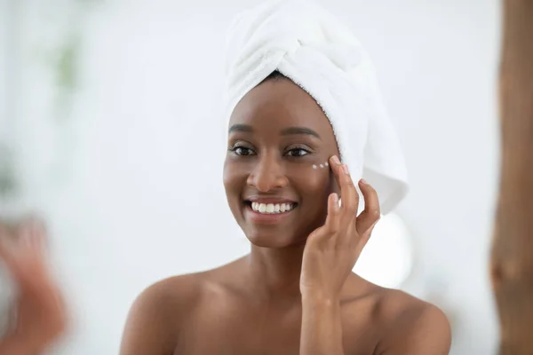 Joyeux jeune blogueuse démontrant de la crème biologique, appliquer sur le visage après la douche le matin — Photo