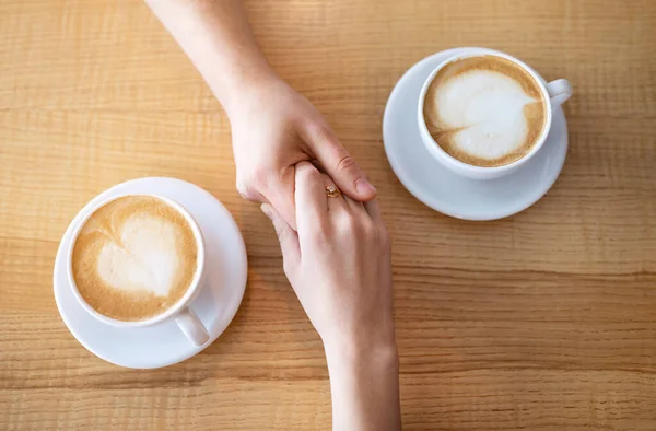 Крупный план тысячелетней пары, держащейся за руки за кофе за столом в кафе — стоковое фото
