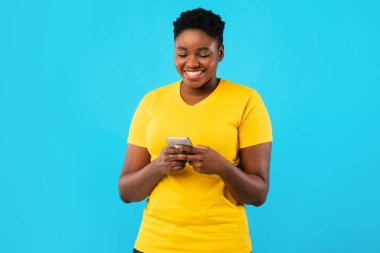 Gülümseyen Siyah Kadın Akıllı Telefon Mesajını Mavi Arkaplanda Kullanıyor