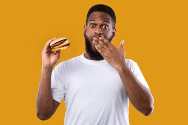 Burger tutan komik siyah adam Sarı Arkaplan üzerinde ağız kaplayan