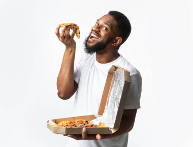 Stüdyoda pizza yiyen aç Afrikalı adam.