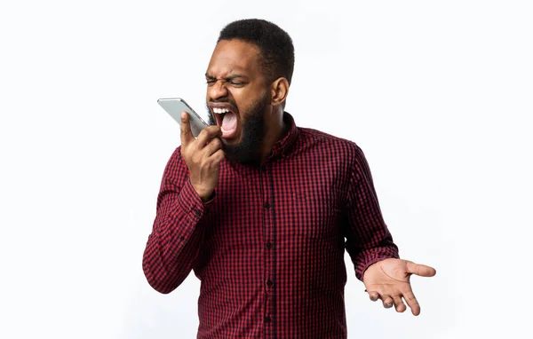 Θυμωμένος μαύρος τύπος φωνάζει στο Smartphone στέκεται πάνω από το λευκό φόντο — Φωτογραφία Αρχείου