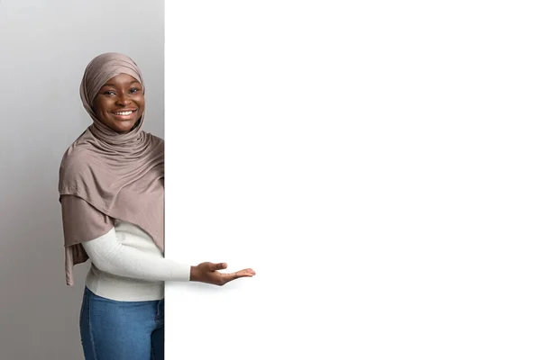 Intresting Offer. Happy Black Woman In Hijab Pointing At White Advertisement Board — Stock Photo, Image