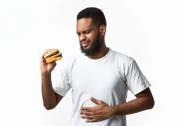 Africano cara ter dor de estômago depois de comer hambúrguer em fundo branco — Fotografia de Stock