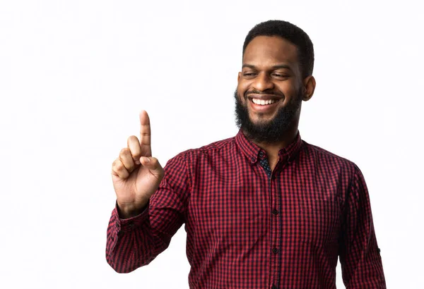 Sonriente hombre africano sosteniendo objeto invisible en el dedo, fondo blanco — Foto de Stock