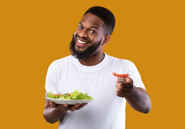 Cheerful Black Man Comendo Veggie Salada Segurando Placa, Fundo amarelo — Fotografia de Stock