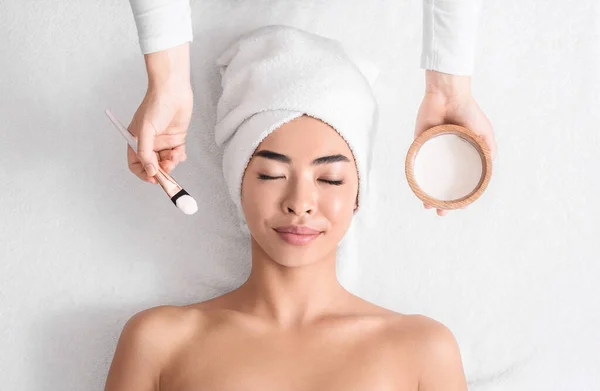 Relajada mujer asiática acostada en la mesa de spa lista para tratamientos de belleza facial — Foto de Stock