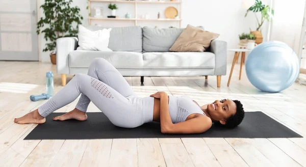 Millennial femme noire au repos après l'entraînement, couché sur un tapis de yoga à la maison — Photo