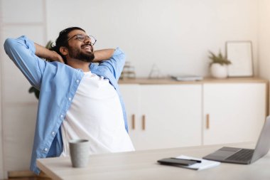 Neşeli Arap Serbest Çalışan Adam, başarılı bir işten sonra geriye yaslanıyor ve dinleniyor.