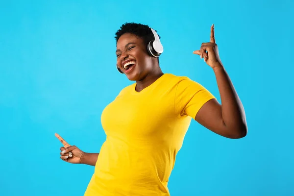 Plus-Size Black Lady escuchando música bailando sobre fondo azul — Foto de Stock