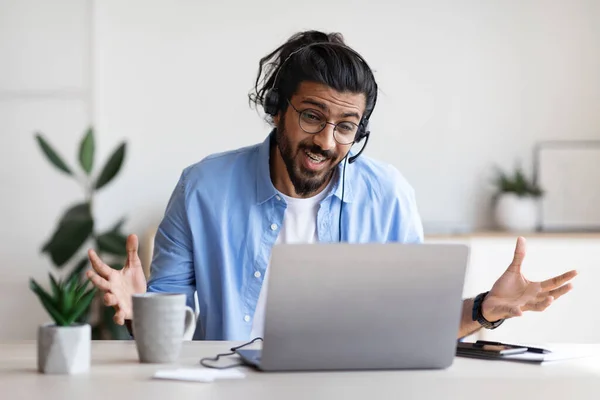 Kulaklıklı neşeli bir Arap 'ın laptopuyla ofiste görüntülü görüşmesi var., — Stok fotoğraf