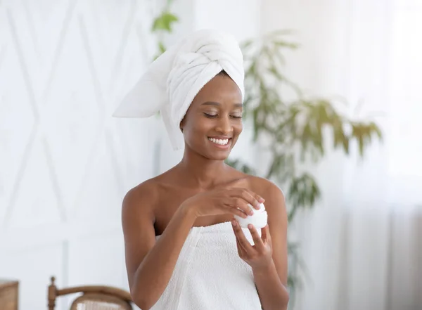 Cosméticos contra rugas e problemas de pele. Jovem feliz afro-americano blogueiro feminino abre frasco de creme — Fotografia de Stock