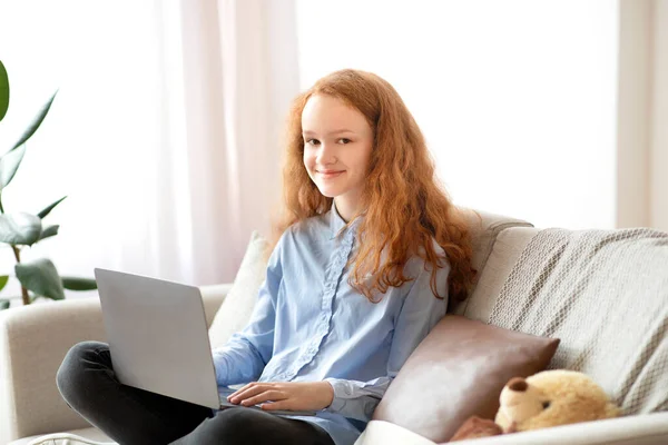 Chica sentada en el sofá y el uso de su ordenador portátil — Foto de Stock