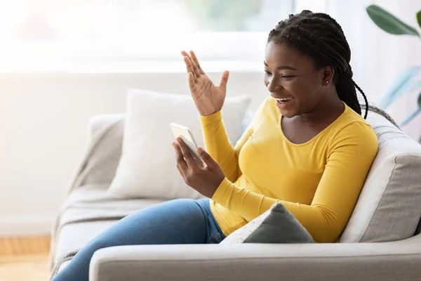 Förvånad svart kvinna gör videosamtal på smartphone hemma, känslomässigt Gesturing — Stockfoto