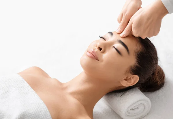 Приваблива молода кореєчка, яка має масаж голови в спа-салоні. — стокове фото