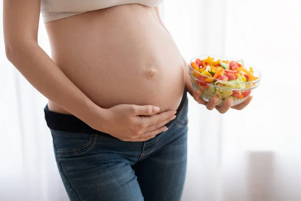 健康的な妊娠のための栄養.妊娠中の女性ベリーの近くで野菜サラダボウルを保持 — ストック写真