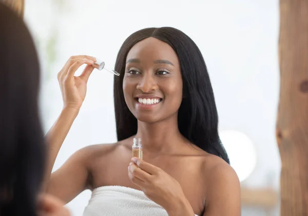 Kosmetologi och spa. Skönhetsporträtt av leende ung afrikansk amerikan kvinna ser i spegeln — Stockfoto