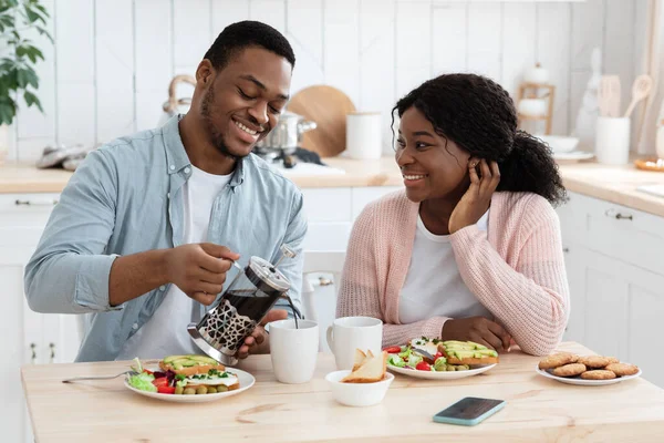 Heureux couple afro-américain manger le petit déjeuner et boire du café dans Kitchchen ensemble — Photo