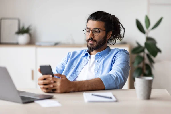 Jovem Empreendedor Árabe Masculino Relaxante No Local De Trabalho Com Smartphone, Navegando Na Internet — Fotografia de Stock
