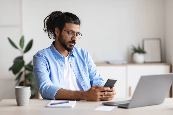 Arabische Freelancer Mann Nachrichten auf Smartphone, am Schreibtisch im Home Office sitzen — Stockfoto