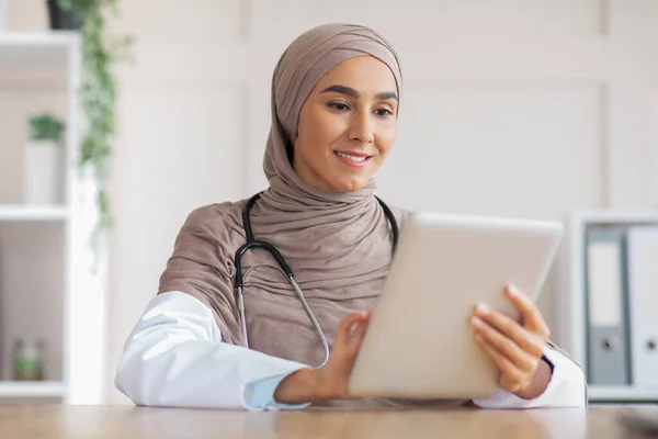 Привабливий мусульманський лікар, який працює в клініці, використовуючи цифровий планшет — стокове фото