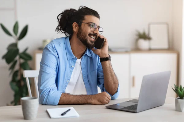 Mladý Arab Man mluví na mobilu, pracuje na notebooku v kanceláři — Stock fotografie