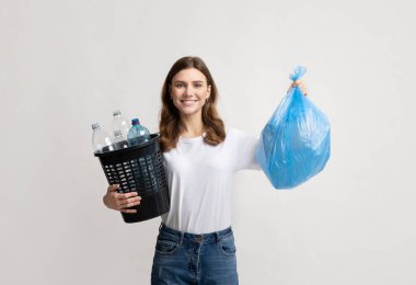 Çöp ayıklama. Gülümseyen kadın elinde plastik şişelerle çöp torbası ve kova tutuyor.