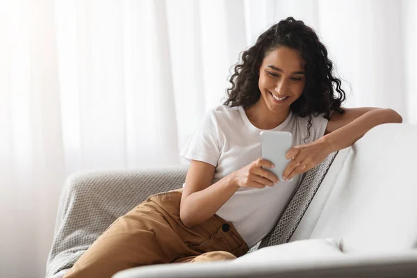 Donna felice utilizzando il telefono cellulare a casa — Foto Stock