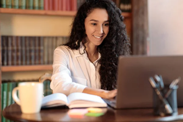 Kvinna sitter vid skrivbordet och använder laptop — Stockfoto