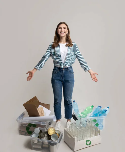Atık ayıklama. Mutlu kadın farklı türde ev çöplerinin arasında duruyor. — Stok fotoğraf