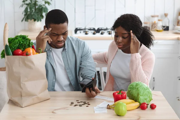 Grocery Expenses. Upset Black Couple Sitting In Kitchen, Looking At Empty Wallet