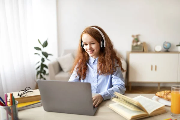 Chica usando auriculares usando ordenador portátil mirando a la computadora — Foto de Stock